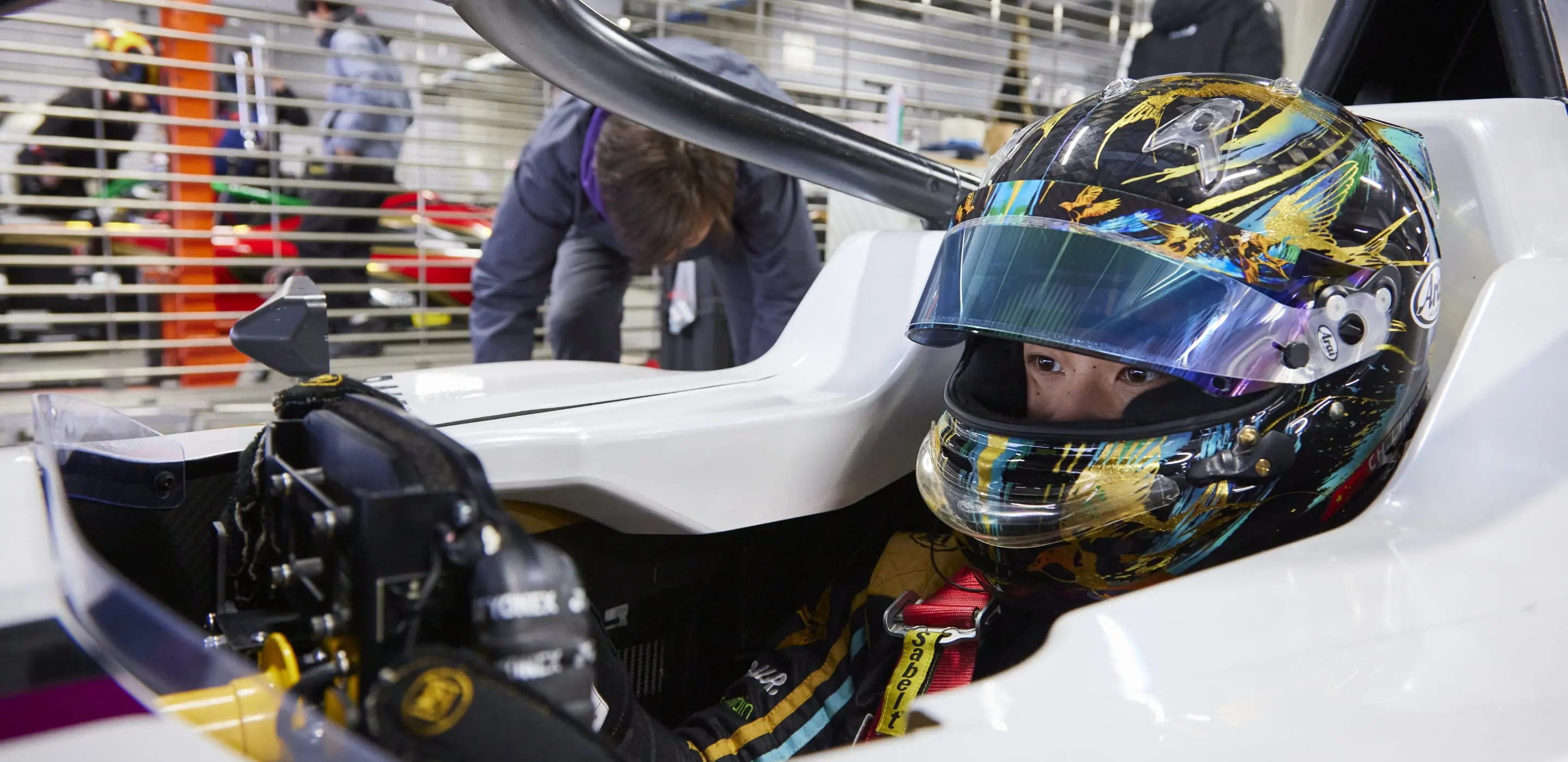 レーシングヘルメットをかぶったドライバーがコックピットに座り、走行準備をしている様子